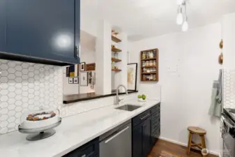 Honeycomb backsplash, quartz countertops, open wall into the living room exposing brick with custom walnut shelving.