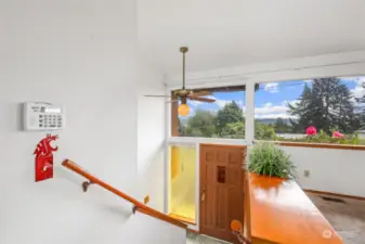 Split entryway with slate floor, amber side lite, ceiling fan and windows above door