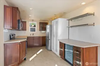 Full kitchen with wood cabinetry, tile flooring, stainless appliances, subway tile backsplash, and a wine fridge
