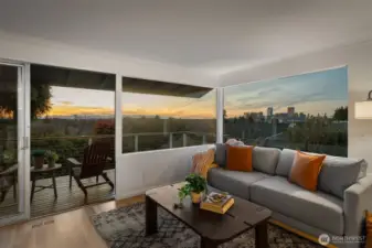 Walls of windows frame breathtaking sunset views, filling the living space with warm natural light and showcasing sweeping vistas of Bellevue, Seattle, and the Olympic Mountains.