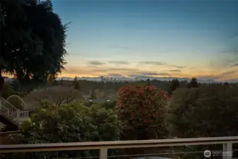 Serene backyard setting at dusk with lush greenery and glowing skies, creating a peaceful backdrop with distant city and mountain silhouettes.