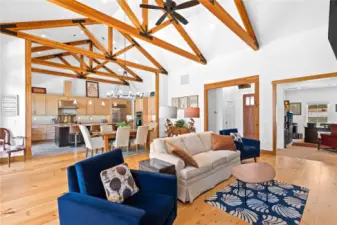 View 4 of the Living Room and Dining Room with soaring ceilings, exposed wood beams, wide plank wood floors, stone fireplace and glass sliding doors leading to the outdoor living area.