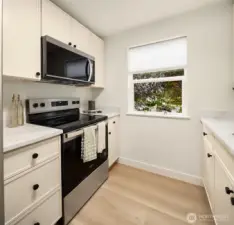 Cream thin shaker cabinets with quartz countertops and new appliances