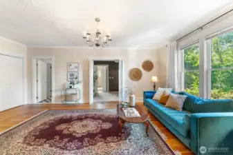 Large, sunlit living room with hardwood floors and double-door entry into additional living space.