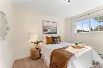 Main floor bedroom 2. Cozy bedroom with neutral tones, natural light from a large window, and plush carpet underfoot.