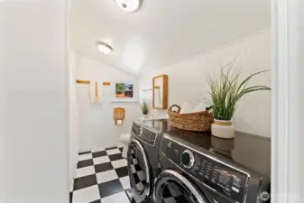Convenient main floor laundry and full bathroom with modern washer/dryer, black-and-white flooring, and dual access from the kitchen eat-in area and formal dining room. Ideal for busy households or multigenerational living