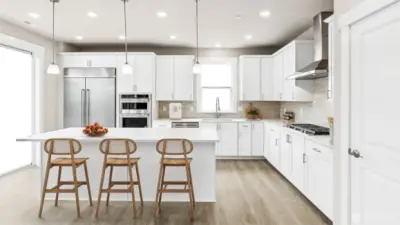 Bright kitchen with oversized island seating, crisp cabinetry, stainless steel appliances, and generous prep space. Alternate color palette displayed for this plan.  White cabinets are an upgrade.