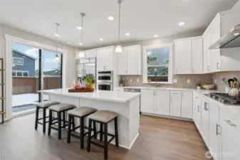 Generously sized kitchen with spacious island seating, crisp cabinetry, stainless steel appliances, and generous prep space.  Showing another staged home in the community, white cabinetry is an upgrade.