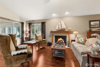 This the family room with warm walnut floors, a gas fireplace and vaulted ceiling. Currently many cozy vignettes set up in this room, there truly is room to spread out with a nice sectional or a minimal style furniture layout.