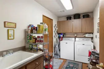 Laundry room (just off the kitchen) with a deep sink is spacious enough for plenty of storage. Door to the left is the entry to the garage.