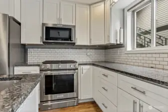 Remodeled kitchen with granite counters, gas range, air fryer microwave, tile backsplash, eating bar, recessed lights and vinyl plank flooring.  Opens to dining room and living room.