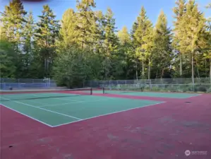 Double tennis courts near clubhouse w/community gardens beyond