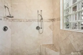 The spacious primary suite shower has dual shower heads.