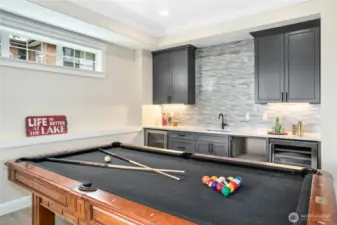 This kitchenette was designed with entertaining in mind. Note: cabinets for storage, sink with tile backsplash, small refrigerator and wine frig. A microwave has been added since this photo was taken. Clerestory windows ensure natural light. Crown molding ties this room in with the rest of the home.