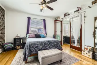 Truly spacious bedroom with French doors, views of the city, and gorgeous exposed brick. Don't miss the walk in closet with custom shelving.