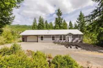 Charming front exterior with private, wooded surroundings.