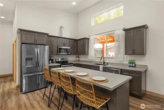 Sleek modern kitchen with quartz counter tops, stainless steel appliances and a large island with bar seating perfect for entertaining.