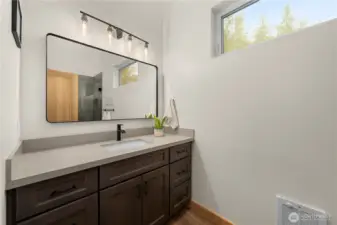 Primary bathroom features a quartz countertop vanity and an oversized high window that fills the space with natural light.