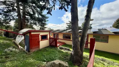 Energy-efficient home featuring 33 solar panels and double windows, chicken coop wood shed, raised garden beds plus older greenhouse.