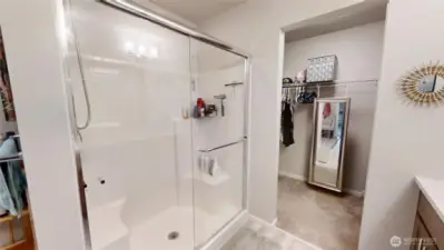 Primary bathroom looking on to large walk in closet.