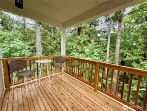 Cedar deck off of kitchen eating area with green trees on the back and side creating a private oasis.