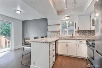 Kitchen with range, dishwasher, microwave and stone countertops.