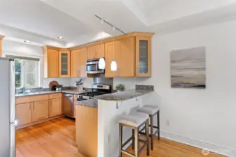 The remodeled kitchen has custom maple cabinets extending to the ceiling and large chrome bar pulls.  The eating bar has two designer pendant lights.