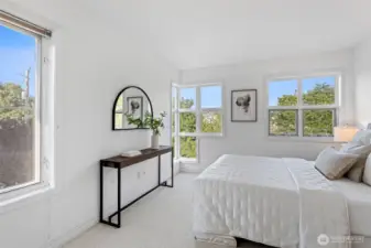 The spacious primary bedroom with a wall of windows looks out to lush green space and territorial views.