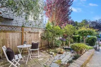Private, fenced front yard with patio for dining, reflective pond and fountain and mature landscaping.
