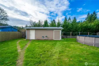 A large shed with two doors—including a sliding barn door—offers easy storage for lawn equipment, pool toys, and larger items.