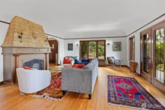 Spacious living room featuring a classic fireplace, abundant natural light, and views through French doors to the sunny back patio and Sound views