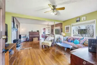 An expansive open-concept living area boasts hardwood floors, a gas fireplace, and a large picture window that floods the space with natural light.