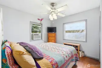 The primary bedroom features original hardwood flooring, dual windows for natural light, and ceiling fan.
