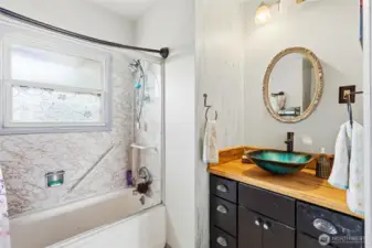 This bathroom features an updated vanity, and  tub/shower combo with a window for natural light and fresh air.