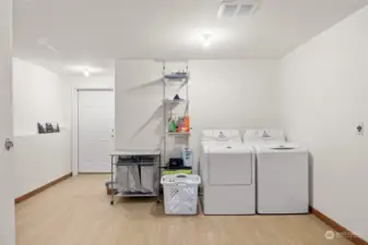 Nice sized laundry space has new LVP flooring, & plenty of space for additional bunks, workout space, or office! This houses the mechanical room & also has an exterior exit.