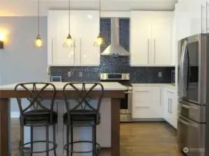 KITCHEN ALSO BOATS ISLAND SEATING BEAUTIFUL SPARKLING BACKSPLASH AND FULL SIZED HOODED FAN OVER THE PROPANE STOVE!