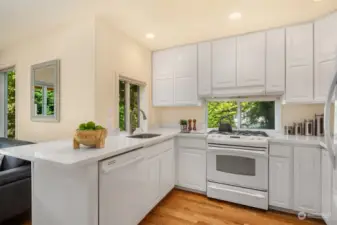 The kitchen has quartz counters, gas cooktop, white-on-white appliances and cabinets that reach the ceiling.