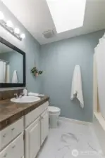 Full bathroom with tile flooring and skylight