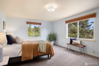 Primary bedroom with South East Facing windows that capture the morning light. offering a peaceful retreat with its ensuite room and views of the surrounding nature and balcony access.