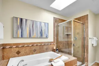 A skylight, soaker-tub, double-sinks and bench turn this en-suite primary bathroom into a spa.
