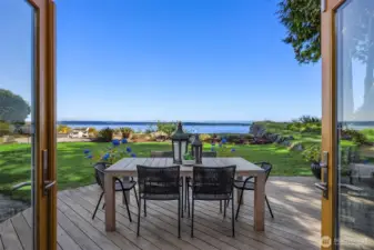 Outdoor dining area on back deck overlooking the lawn and expansive water views, with direct access from the dining room & kitchen areas for easy indoor-outdoor living.