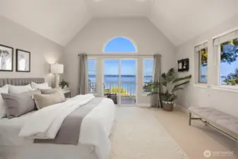 Primary bedroom with vaulted ceilings, private deck access, and expansive water views, creating a bright and spacious retreat.