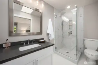 Ensuite bathroom featuring a walk-in glass shower with tile surround, modern vanity, and updated fixtures.