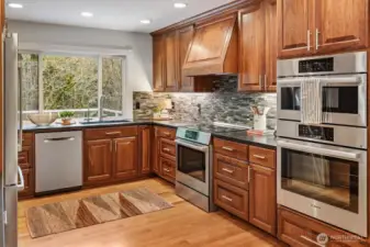This gorgeous kitchen black quartz countertops, all Bosch appliances, an induction stove and hooded vent, backsplash throughout. Not to mention the large picture window overlooking the back of the property.