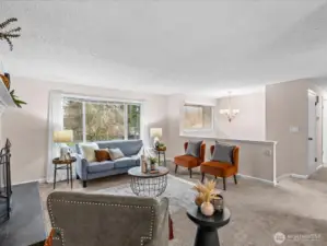 The living room feels open and comfortable, with a large picture window that frames views of the surrounding trees.