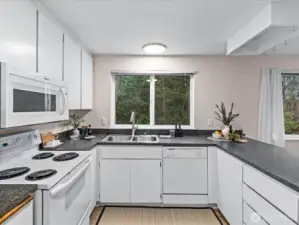 A large window above the sink frames tranquil views of greenery, bringing the outdoors inside.