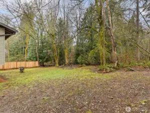 A spacious, partially fenced backyard with a creekside setting provides room to create your ideal outdoor space.