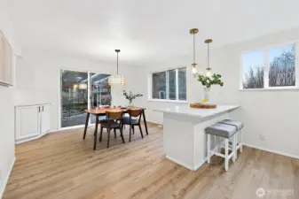 The light-filled dining area is anchored by a woven pendant light and sliding glass door to the backyard, making indoor-outdoor dining a natural extension of daily living.