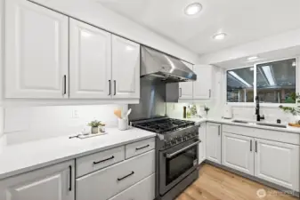 Close-up detail of the professional gas range, stainless hood, and quartz countertops highlight the quality finishes that make this kitchen a standout for serious home cooks.