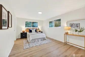 The primary bedroom impresses with dual windows overlooking the lush backyard, warm LVP flooring, and plenty of room to spread out.